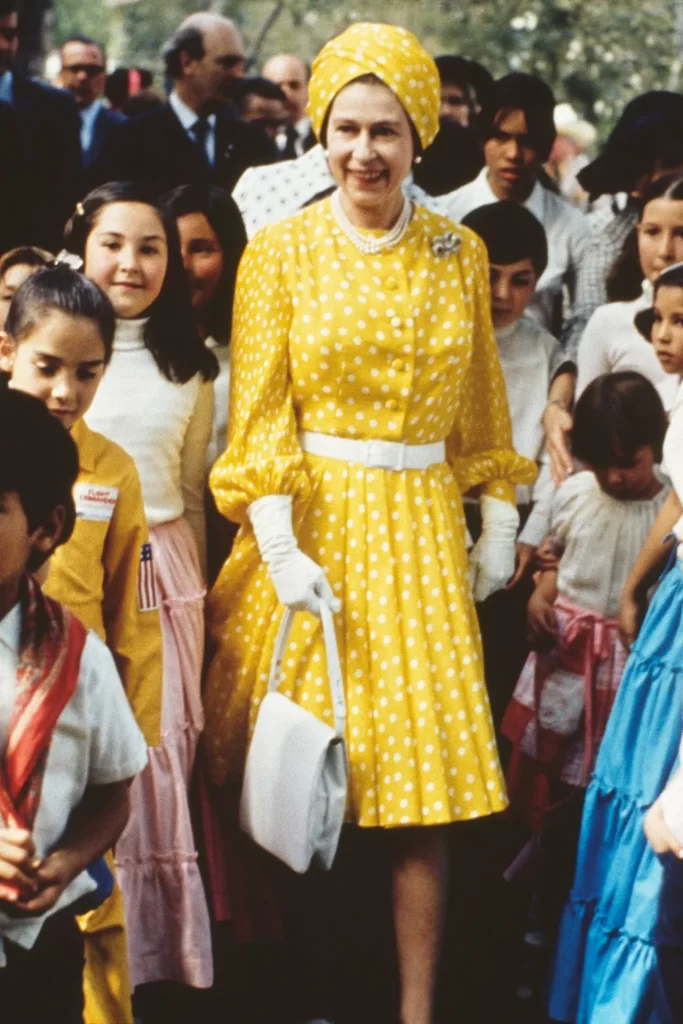 February 1975 Queen Elizabeth spent time with a group of local children during her state visit to Mexico wearing a marigold printed pleated dress and a turban-style hat.